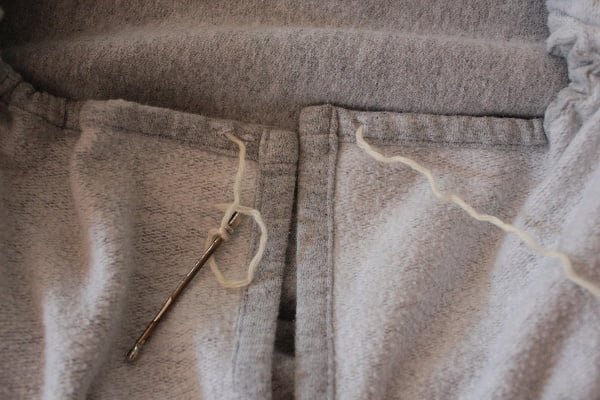 Thread yarn through the hem/casing of the blanket with a bodkin or safety pin.
